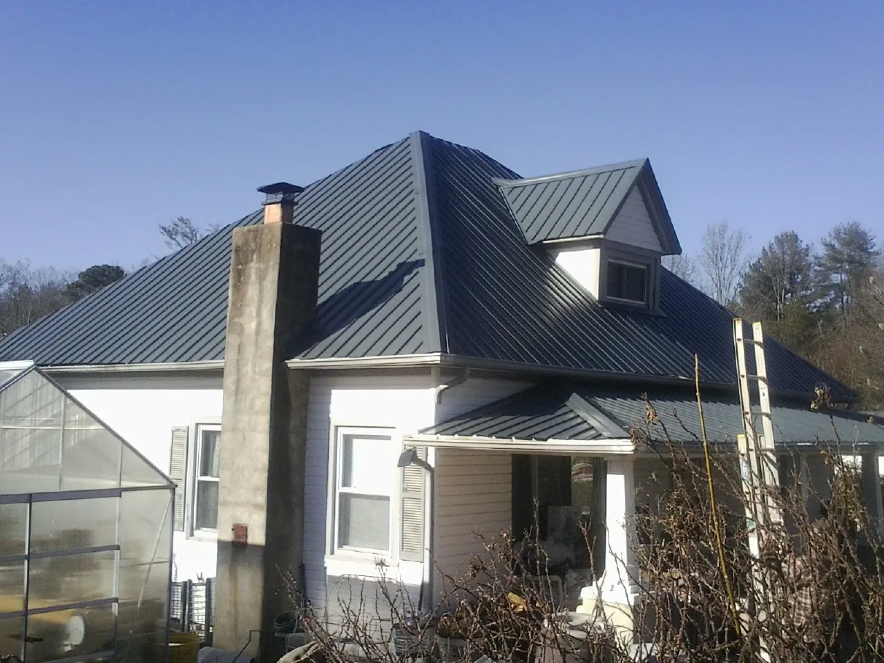 Dark blue standing seam metal roof on a white farmhouse with dormer — Slate & Tile Roof Repair by Roofing Brothers in Childwold