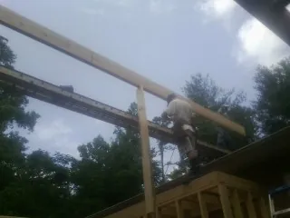 Carpenter setting a ridge beam over a new addition frame — Ice Dam Removal by Roofing Brothers in Childwold