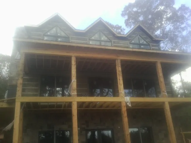 Dormers and porch framing on a large log home under construction — Roof Coating work by our crew in Childwold