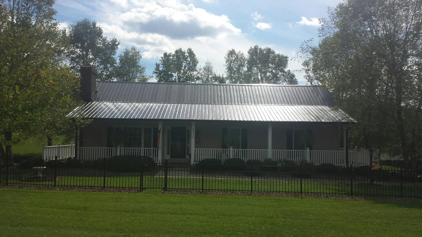 Gray metal roof on a brick ranch with a full width front porch — Gutter Guard Installation work by our crew in Childwold