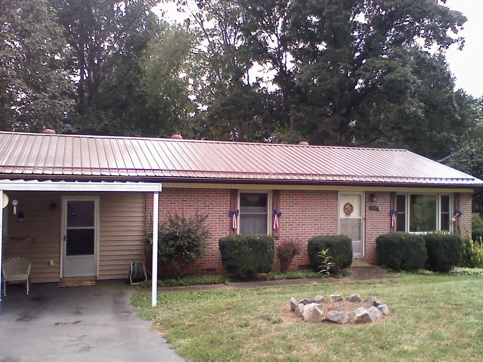 Bronze metal roof and carport on a brick ranch home — Roof Repair work by our crew in Childwold