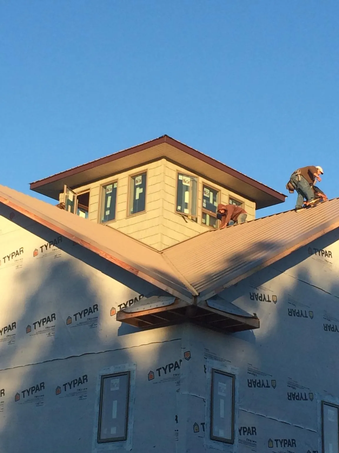 Roofers working around a rooftop cupola on a new metal roof at sunset — Roof Waterproofing in Childwold by Roofing Brothers